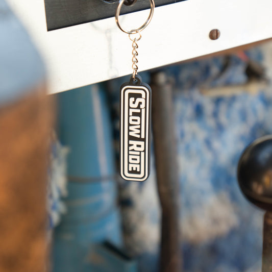 Radio Keychain - Slow Ride- Classic Slow Ride keychain featuring the iconic 'Slow Ride' logo in black and white, perfect for fans of Off-Roading and Off-Road Racing. This keychain is an ideal accessory for vintage Volkswagen enthusiasts, including those who love the Volkswagen bus, Volkswagen bug, and Baja bug. A great addition to any Garage and Racing lifestyle, this keychain embodies the spirit of Slow Ride Garage and mottos like 'Enjoy Getting There,' 'Wheelin and Spilling,' and 'Restore and Destroy.' A 