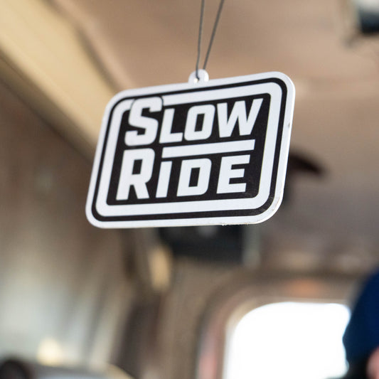 Radio Stack Air Freshener - Slow Ride- Retro Slow Ride air freshener featuring the classic logo, hanging from the rearview mirror of a vintage Volkswagen bus. Perfect for Off-Roading and Off-Road Racing enthusiasts, this accessory celebrates the iconic Volkswagen culture, including the Volkswagen bug and Baja bug. Ideal for those who live the Garage and Racing lifestyle and embrace mottos like 'Enjoy Getting There,' 'Wheelin and Spilling,' and 'Restore and Destroy.' A must-have for blue-collar workwear fans
